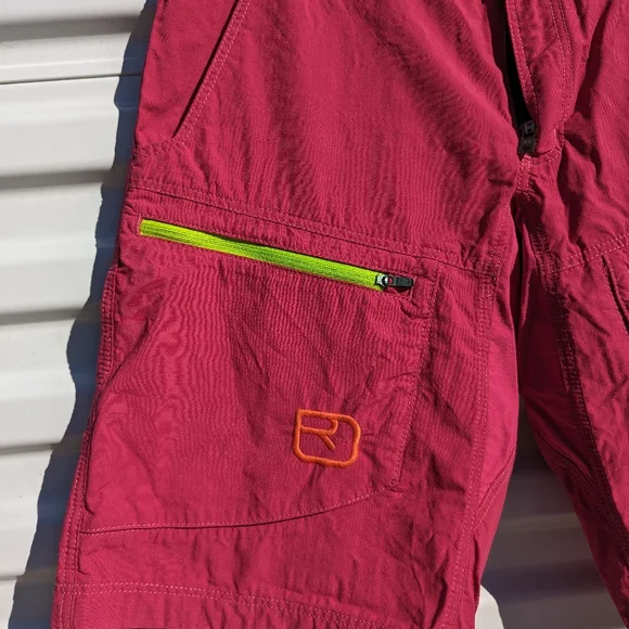Ortovox fuscia hiking shorts with yellow and orange accents